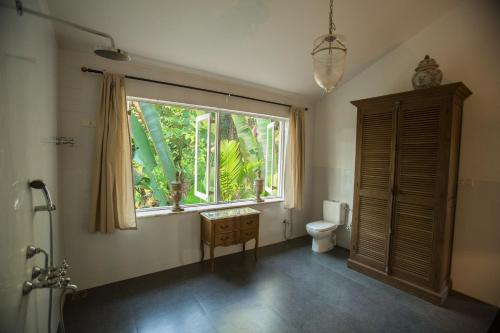 a bathroom with a toilet and a large window at Lua Cheia Villas Sadoxlem in Canacona