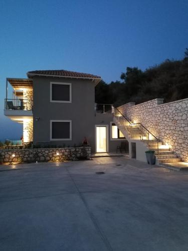 a house with a staircase in front of a building at MELIKIRON LUXURY APARTMENTS in Agios Nikitas