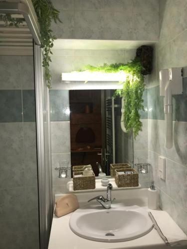 a sink in a bathroom with a mirror and a mirror at Nid Douillet à la Louvée in Combloux