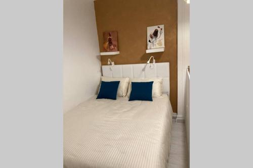 1 dormitorio con 1 cama blanca grande con almohadas azules en Studio COSY et confortable aux PORTES DE PARIS!, en Saint-Denis