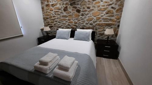 um quarto com uma cama e uma parede de pedra em Casa do Vale da Mula em Almeida