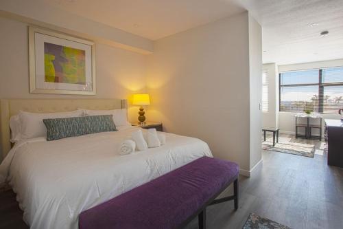a bedroom with a large white bed with a purple bench at Luxurious Design One Bedroom Apt near Balboa Park in San Diego