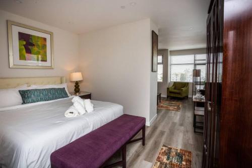 a bedroom with a large white bed with a purple bench at One Bedroom Apartment with Luxurious Furnitures in San Diego