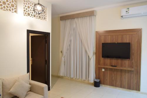 a living room with a television and a couch at منام الخزامى للشقق المخدومة in As Sulaymānīyah