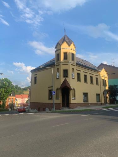 a large yellow building with a tower on top of it at Apartmán na horách in Vejprty