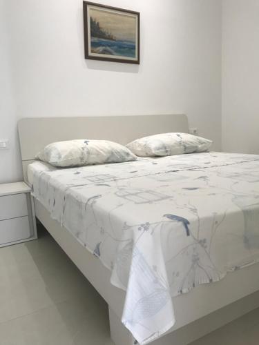 un letto bianco in una stanza bianca con un piumone bianco di Villa Maria a Zara (Zadar)