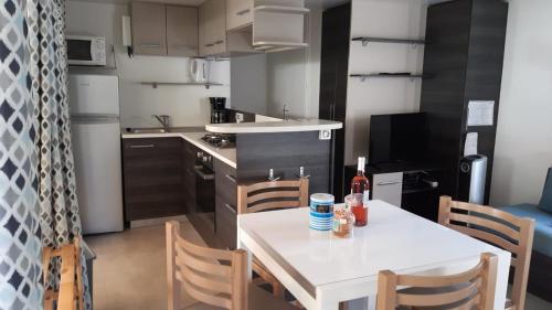 a small kitchen with a white table and chairs at Les Charmettes - SIBLU in Les Mathes