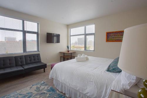 a bedroom with a bed and a couch and windows at Modern, Luxurious and Prime location All in One in San Diego