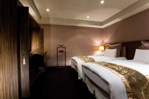 a hotel room with two beds with white sheets at H.M.Hotel in Hsinchu City