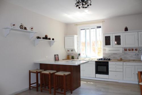 a kitchen with white cabinets and a island with bar stools at Il giardino del casciar in Castel Volturno