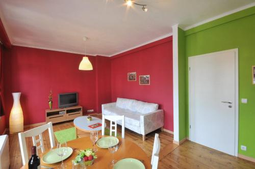 a living room with red walls and a table and chairs at Les Appartements Â Vî Mâm'dî in Malmedy