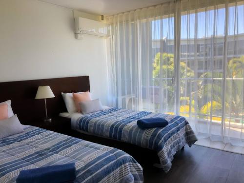 two beds in a hotel room with a window at 2 Bedroom Apartment , Hope Island , Resort living in Gold Coast