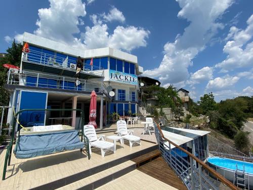 a building with a deck with chairs and a pool at Villa Jackie in Golden Sands