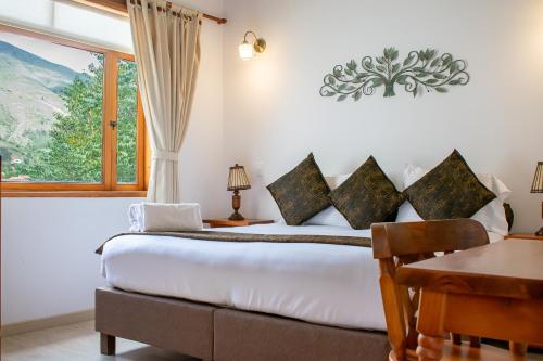 a bedroom with a bed and a table and a window at Hotel El Giro in Villa de Leyva