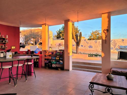 a library with tables and chairs and a large window at La Ventana Hostel in La Ventana