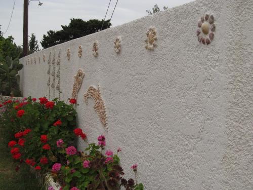 a white wall with flowers on it next to a fence at Saint Amon Hotel in Faliraki