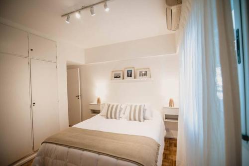 a white bedroom with a bed and a window at Recoleta White Home in Buenos Aires