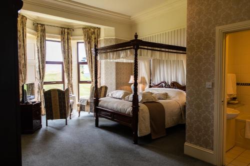 a bedroom with a canopy bed and a bathroom at Ballinalacken Castle Country House Hotel in Doolin