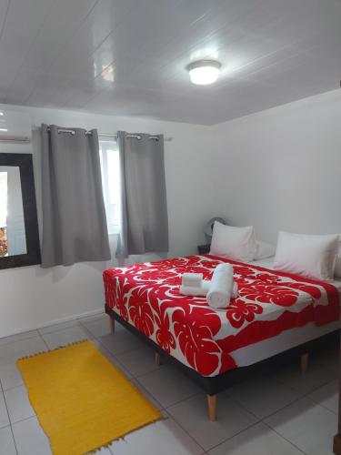 ein Schlafzimmer mit einem roten und weißen Bett mit einem gelben Teppich in der Unterkunft BUNGALOW PAMATAI in Faaa
