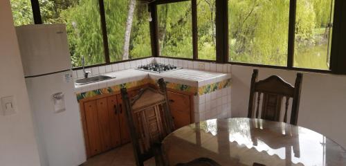 cocina con mesa, 2 sillas y ventanas en Hacienda Moncora cabaña lago p2, en El Rosal