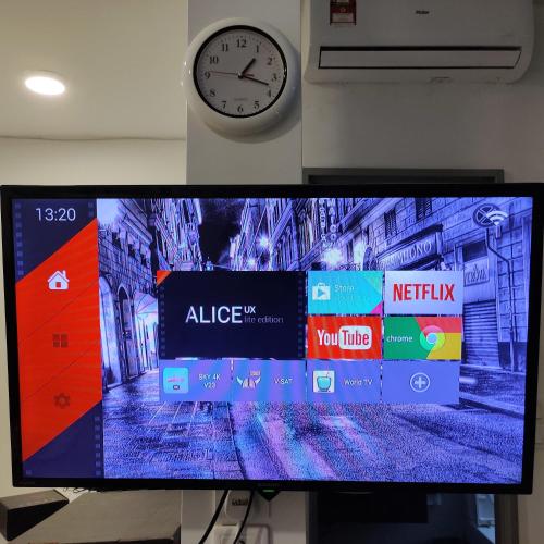 a flat screen tv with a clock on a wall at Comfort Zone Premium Guesthouse @ Evo Bangi in Bangi