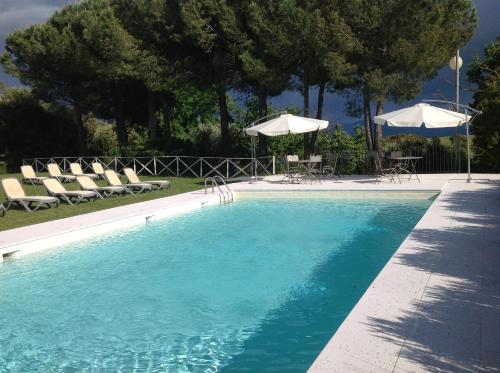 a swimming pool with chairs and umbrellas at Antico Casale L'impostino in Civitella Marittima