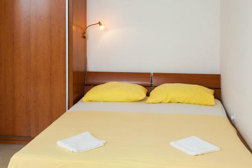 a bed with two yellow pillows in a room at Maki Apartments in Hvar