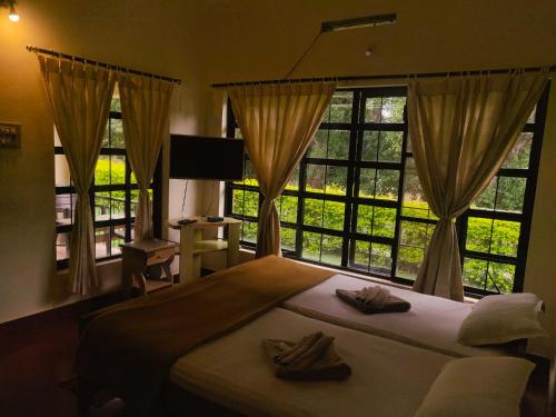 a bedroom with a bed and windows with towels on it at Dubare Inn in Madikeri