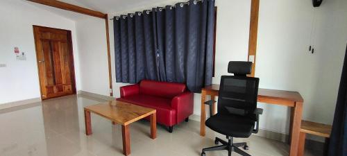 a living room with a red chair and a desk at Le Grand Bleu Hotel in Wok Tum