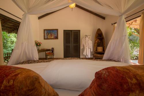 a bedroom with a large white bed with curtains at Rivertrees Country Inn in Usa River