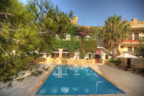 a hotel with a swimming pool in front of a building at Cornucopia Hotel in Xagħra