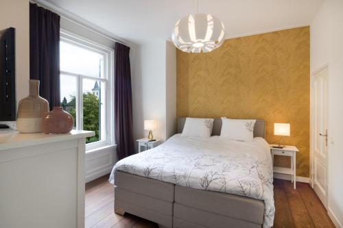 a bedroom with a bed and a window and a chandelier at B&B Villa Kriekenbeek in Lent