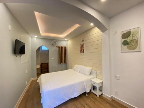 1 dormitorio con 1 cama blanca y TV en Tuyet Mai Hotel en Da Lat