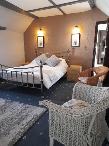 a bedroom with a bed and chairs in a room at The Golden Lion Inn in Denbigh