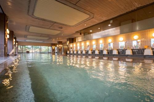 an empty swimming pool with chairs in a building at Hotel Sakurai in Kusatsu