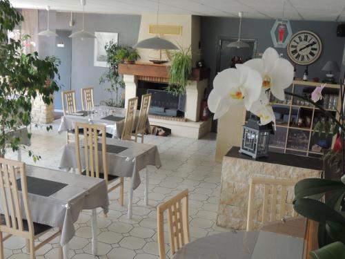 a restaurant with tables and chairs and a clock on the wall at Hôtel auberge des charmilles in Sainte-Soulle