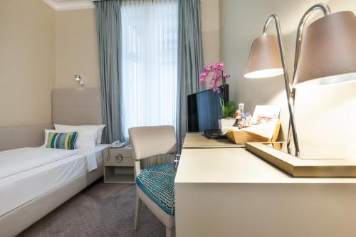 a hotel room with a bed and a desk at Hotel an der Oper in Munich