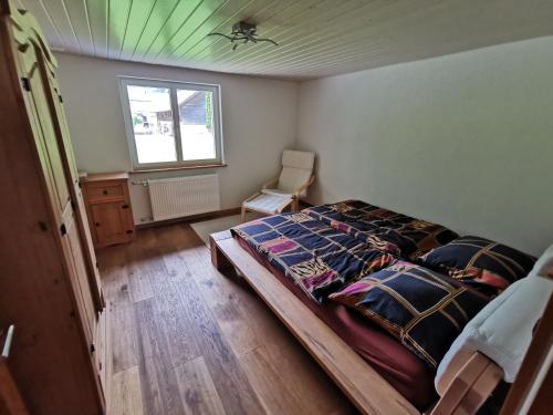 a bedroom with a bed and a chair and a window at Schwendi Maison in Mels