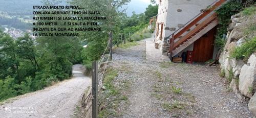 un camino de tierra con una valla al lado de un edificio en Baita Bertolini, en Monclassico