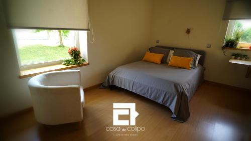 a bedroom with a bed and a chair and a window at Casa Do Colipo in Batalha