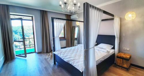 a bedroom with a canopy bed and a large window at Гетьманські палати , Старе місто, 2 спальні, балкон-тераса , 85 м кв in Kamianets-Podilskyi
