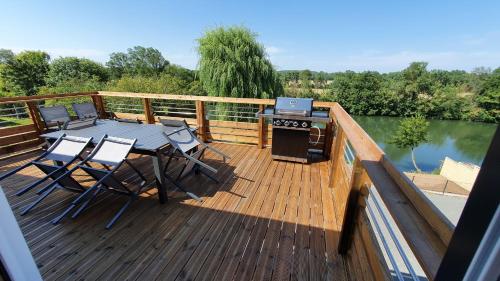 a deck with a table and chairs and a grill at Gîte La Terrasse du Loir à 2km du Zoo de la Flèche in La Flèche