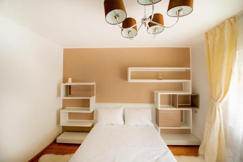 a bedroom with a bed with white shelves and a chandelier at Apartament Beatrice in Râşnov