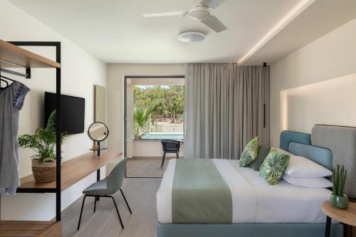 a hotel room with a bed and a desk and a television at Mossa Well Being Hotel - Heated pool in Kato Daratso