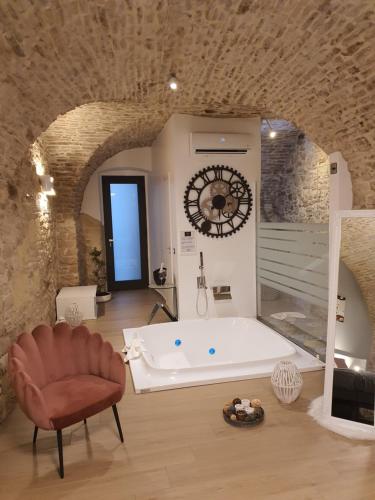 una grande vasca da bagno in una stanza con orologio di Suite 123 Luxury B&B Con Jacuzzi a Palo del Colle