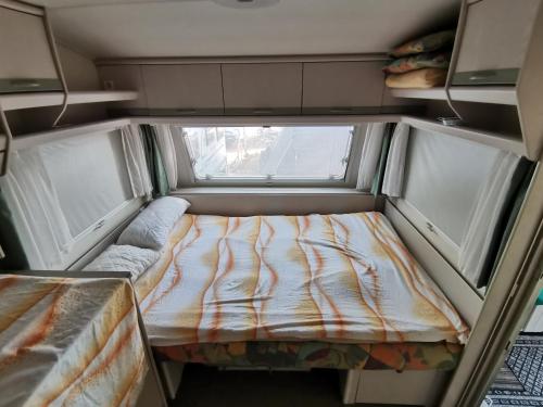 a small room with a bed and two windows at Caravan near the sea 5 in Ugljan