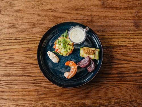 a plate of food with seafood on a wooden table at Hotel Erasmus - Mein Genuss- und Wellnesshotel in Trassem
