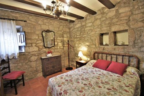 1 dormitorio con cama y pared de piedra en Cal Terri Rural, en Perafita