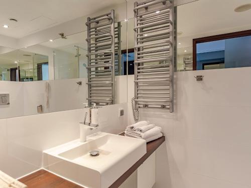 a white bathroom with a sink and a mirror at VacationClub – Marine Hotel Apartament 437 in Kołobrzeg