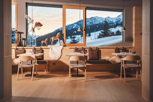 a restaurant with tables and chairs in front of a window at Olympic SPA Hotel - Adults Only in Vigo di Fassa